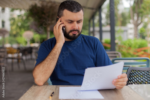 Serious man reading a document and talking on the mobile phone