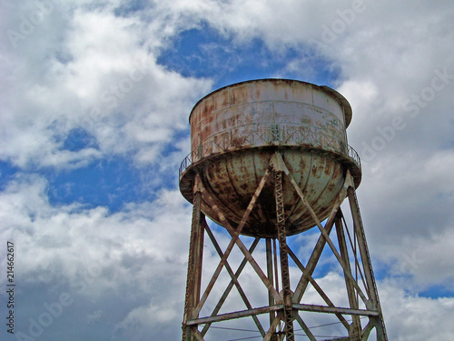 Rusty Water Tower against Cloudy Blue Sky