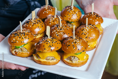 Mini chicken burgers on white plate.