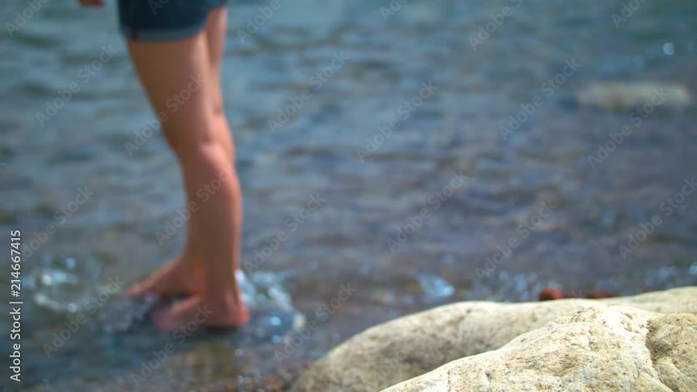 Woman Standing on and Stepping off a Rock on the Lakeshore. Shot on a Blackmagic Ursa Mini Pro 4.6k with a Sigma 50-100mm f/1.8. Woman Standing on and Stepping off a Rock on the Lakeshore. Shot on a Blackmagic Ursa Mini Pro 4.6k with a Sigma 50-100mm f/1.8.