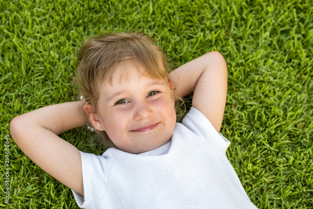 Adorable smiling girl laying in the grass with hands behind head Adorable smiling girl laying in the grass with hands behind head