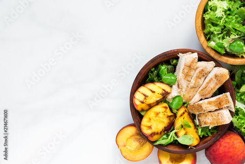 Chicken salad with grilled peach and mixed salad in a bowl. healthy food. top view