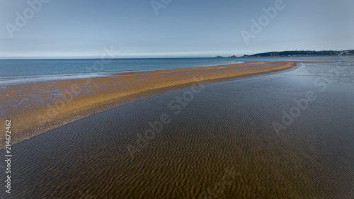 A sandbar in Swansea Bay exposed at very low tide  with Mumbles pier and lighthouse in the distance.