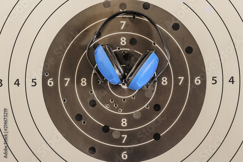 Shooting concept/White and black target with bullets traces and blue ear handphones close up