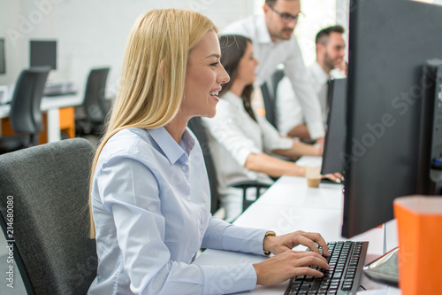 Side view of beautiful blonde hair business woman working on computer in office photo