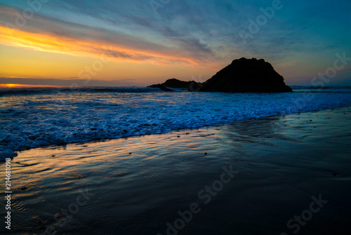 Cannon Beach, Oregon Sunset. The sun sets over a rock outcropping along this Pacific Ocean beach. Miles of lovely white sand with rocky stretches make this a popular tourist destination.