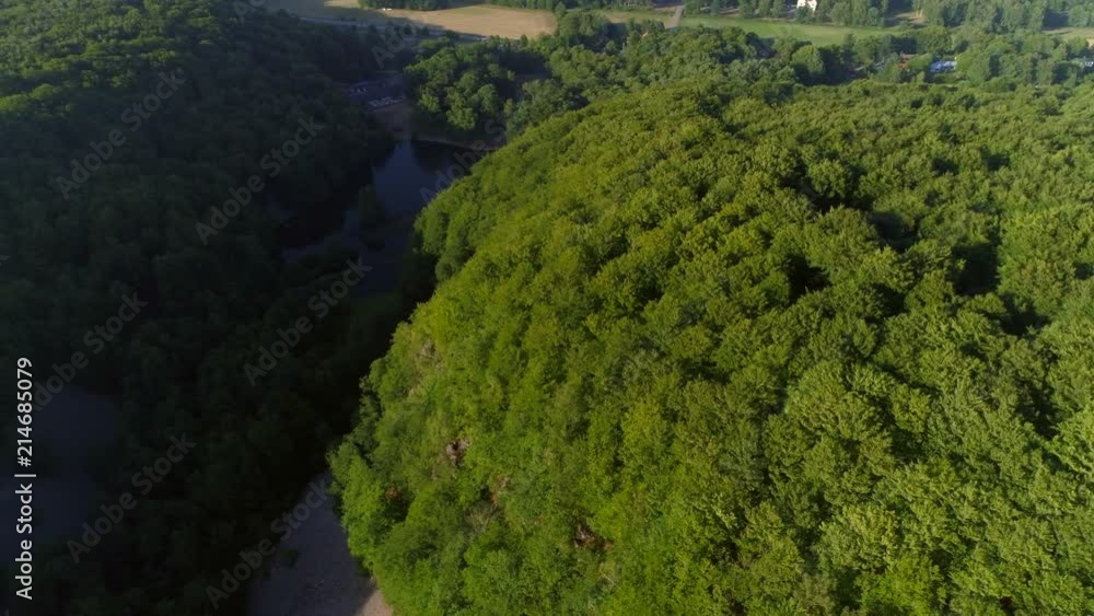 Aerial drone shot flying over valley and pond in deciduous forest in Southern Sweden Aerial drone shot flying over valley and pond in deciduous forest in Southern Sweden