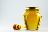 Honey jar with honey dipper on light background
