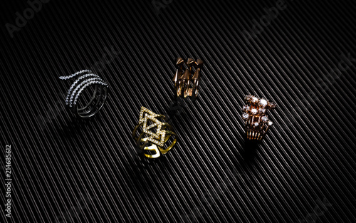 Golden, silver and bronze rings collection on black textured paper