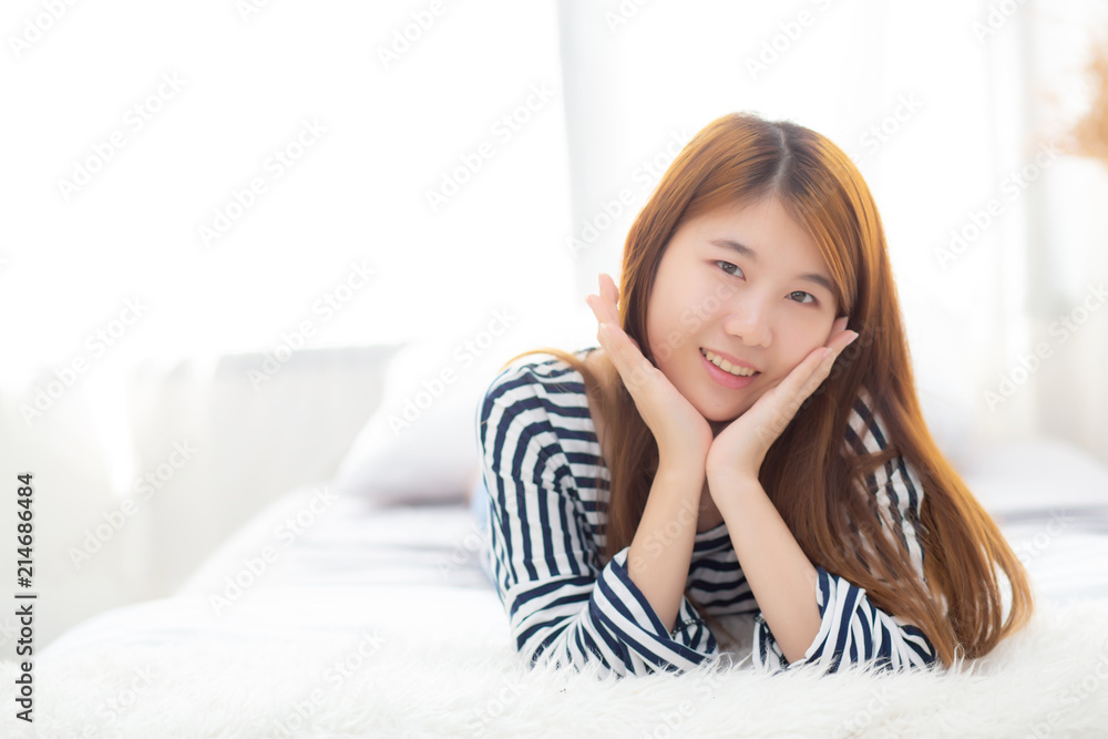 Beautiful portrait young asian woman lying and smile while wake up with sunrise at morning, lifestyle and relax concept.