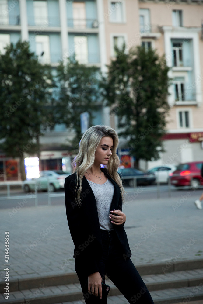 Girl in black trousers and jacket.The blonde in the black suit.Blonde posing in the city Girl in black trousers and jacket.The blonde in the black suit.Blonde posing in the city