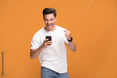 Smiling handsome man with mobile phone on yellow background. photo