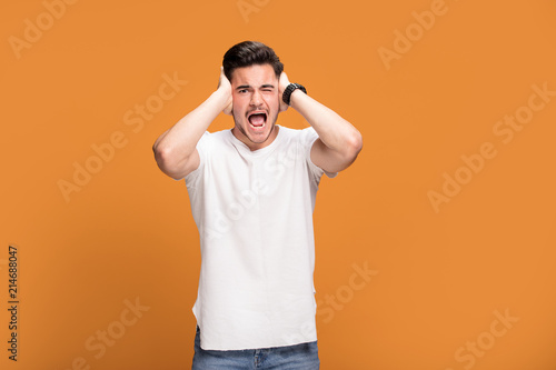 Disappointed young man on yellow background.