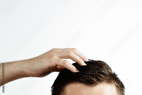 Hand on a man's hair on a white background. A view of brown hair with side hairline isolated on a white background.