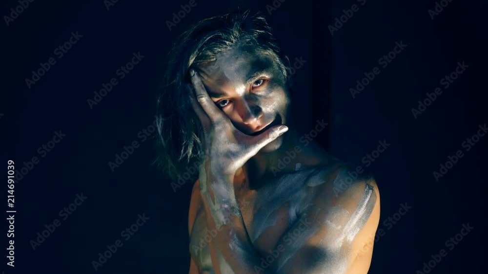 The guy with a gray body copy closes his face with his hand on a black background. Concept of posing for the camera. The guy with a gray body copy closes his face with his hand on a black background. Concept of posing for the camera.