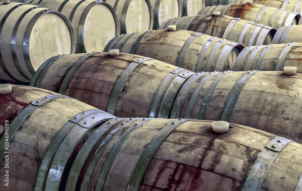 Old and stained wooden wine barrels in rows inside a wine cellar