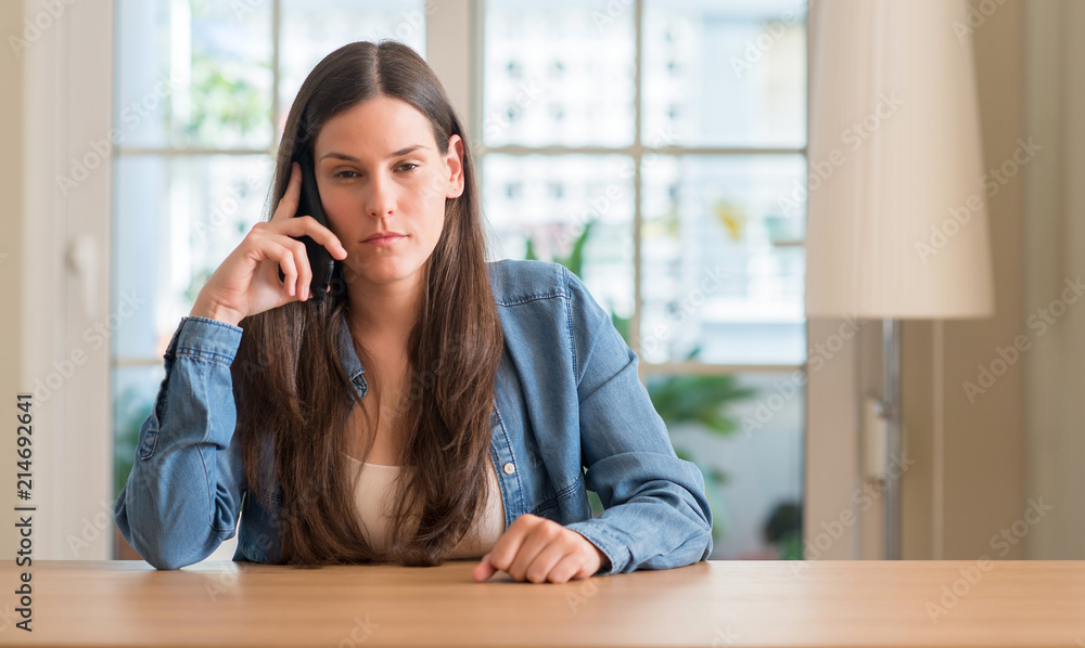 Young woman using smartphone with a confident expression on smart face thinking serious Young woman using smartphone with a confident expression on smart face thinking serious