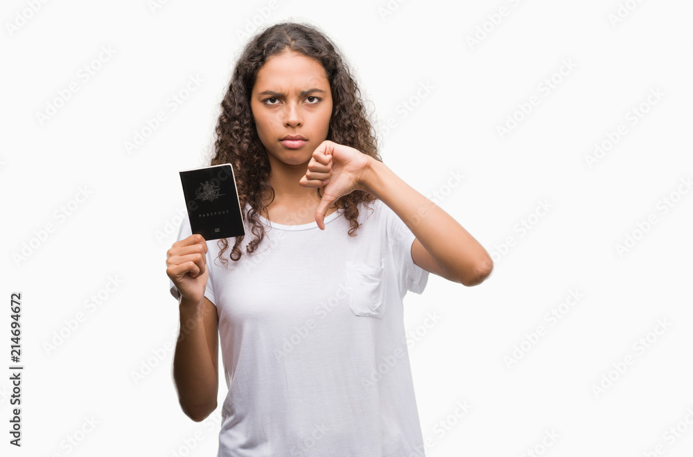 Young hispanic woman holding passport of Australia with angry face, negative sign showing dislike with thumbs down, rejection concept