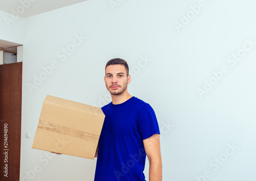 Handsome man holding cardboard box with items. Young family moving in concept.