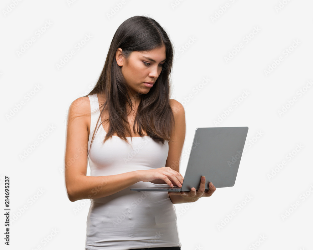 Naklejka premium Young hispanic woman using computer laptop with a confident expression on smart face thinking serious