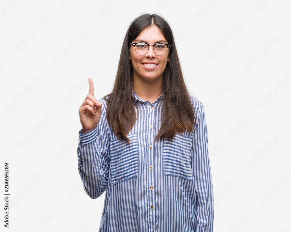 Young beautiful hispanic business woman showing and pointing up with finger number one while smiling confident and happy. Young beautiful hispanic business woman showing and pointing up with finger number one while smiling confident and happy.