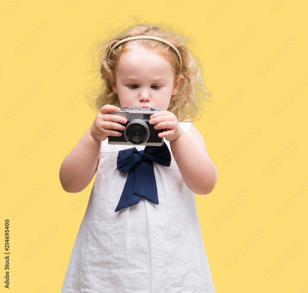 Fototapeta premium Beautiful blonde toddler taking pictures with vintage camera