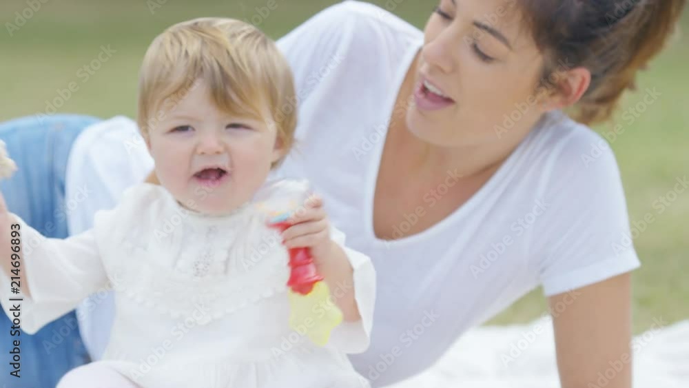 Young mother and daughter in a park playing with baby toys, in slow motion Young mother and daughter in a park playing with baby toys, in slow motion