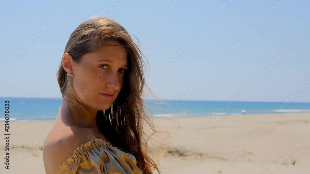 Young beautiful woman standing on sand dunes near the sea. Young beautiful woman standing on sand dunes near the sea.