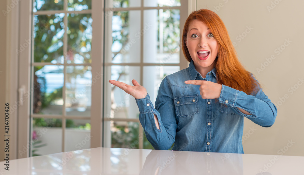 Redhead woman at home very happy pointing with hand and finger