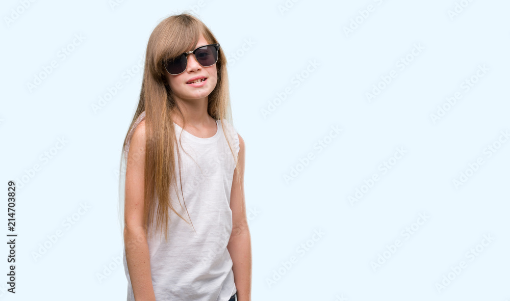 Young blonde toddler wearing sunglasses with a happy face standing and smiling with a confident smile showing teeth Young blonde toddler wearing sunglasses with a happy face standing and smiling with a confident smile showing teeth
