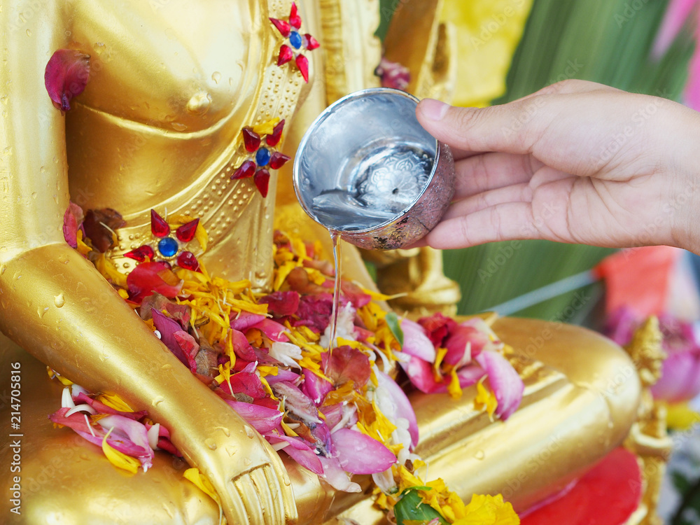 Fototapeta premium Close up hand watering to golden buddha statue