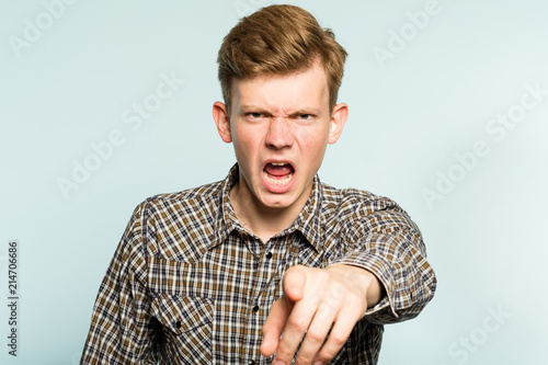 how dare you. angry mad fretful cross man ordering you to do smth. instruction and command. portrait of a young guy on light background pointing a finger. emotion facial expression.