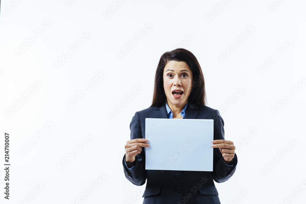 Portrait of an excited woman with mouth open in grey jacket holding blank sign, isolated on white studio background Portrait of an excited woman with mouth open in grey jacket holding blank sign, isolated on white studio background