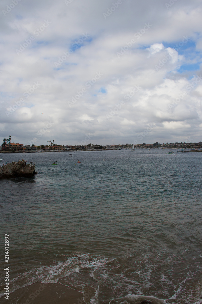 Coastline view from beach shore in Southern California with cityscape and sailing boats in the background. Summer vacations at the beach for relaxation tranquility and peacefulness Coastline view from beach shore in Southern California with cityscape and sailing boats in the background. Summer vacations at the beach for relaxation tranquility and peacefulness