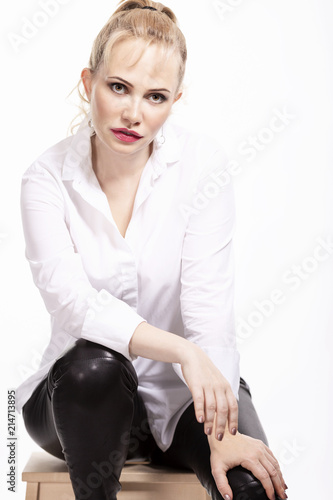 Beautiful woman in a white shirt and leather trousers, isolated on a white background