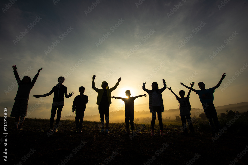 Silhouette of children jumping, happy and fun in the morning grassland, sunrise in nature.