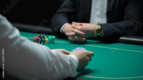 Male croupier shuffling and dealing cards at casino, player checking combination photo