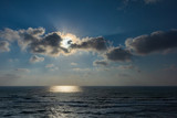 The Sun behind a cloud over the sea, horizontal