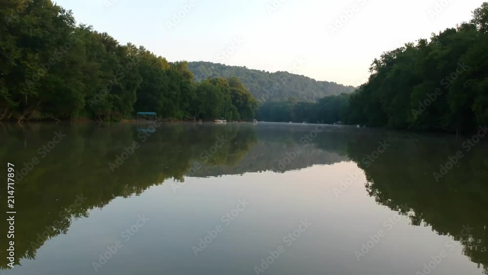 Floating further down the river fine mist of fog in the distance trees reflecting off the smooth water on both sides of the frame. Floating further down the river fine mist of fog in the distance trees reflecting off the smooth water on both sides of the frame.