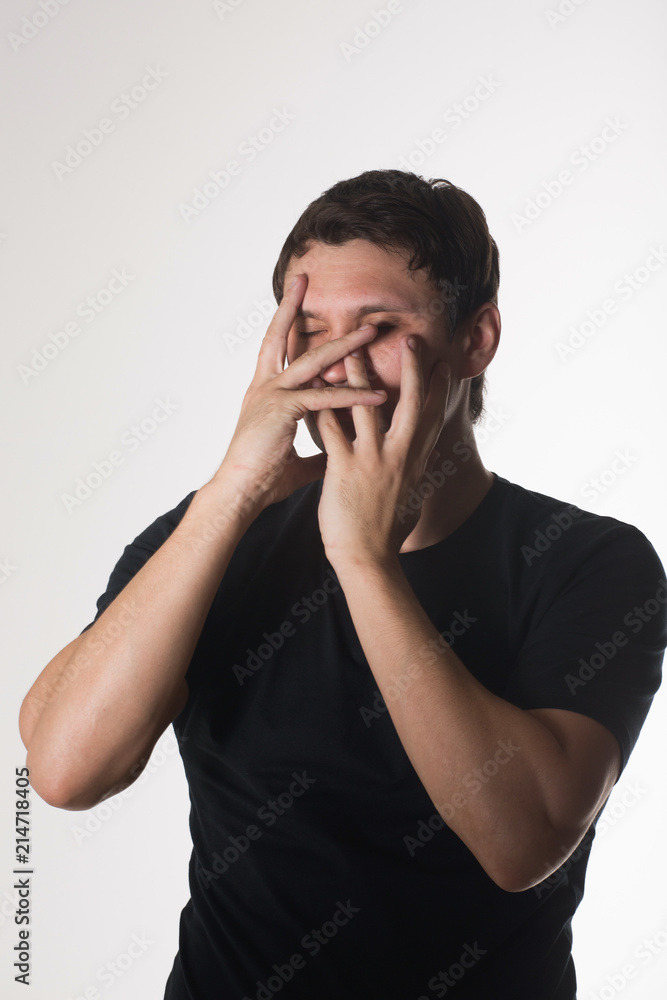 Unshorn and unshaven young guy with piercings on his face, closing his mouth with his hands on gray background. Unshorn and unshaven young guy with piercings on his face, closing his mouth with his hands on gray background.