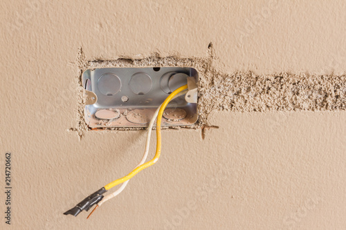 New electrical installation, socket box and electrical cables yellow white on pink wall, renovation concept, home under construction