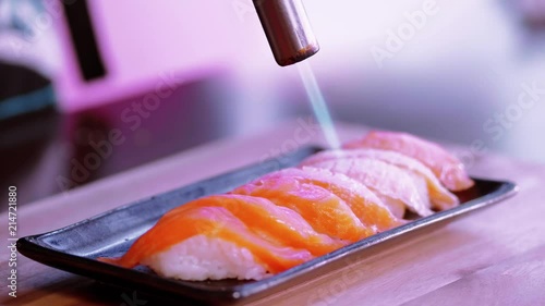 Preparing Sake Nigiri Sushi - flambe salmon by a hot flame photo