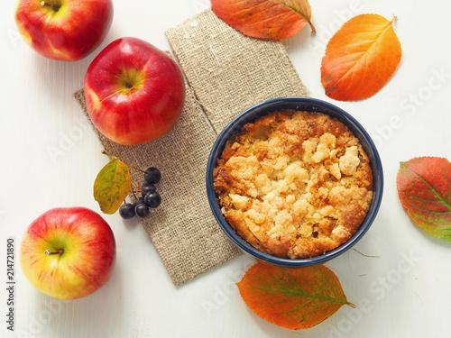 Autumn fruits cake. Homemade crumble with red apples and rowanberry, decorated with bright leaves. Selective focus.
