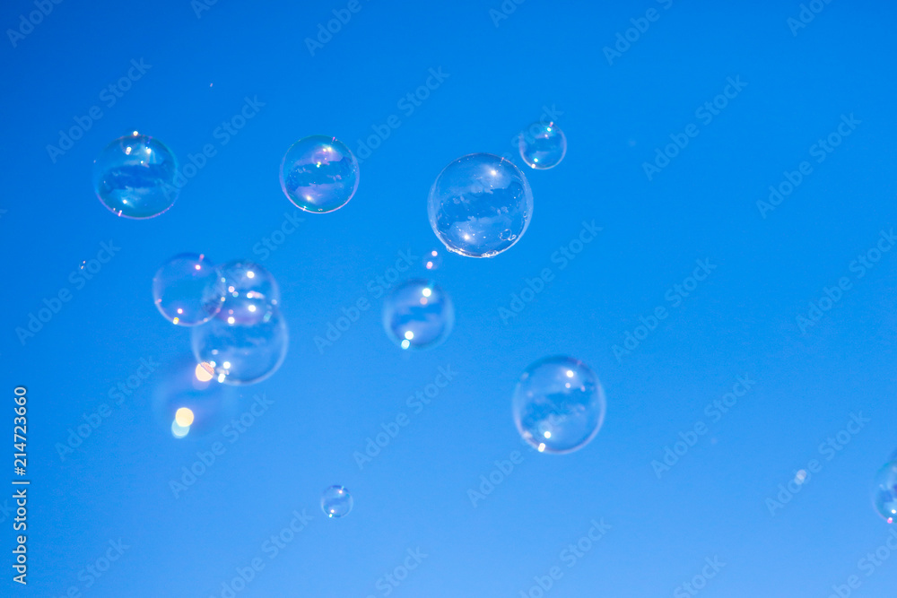 Soap bubbles in flight against the blue sky