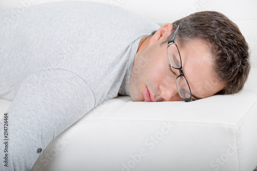 Tableau sur toile Man asleep on sofa, glasses being pushed off of his face