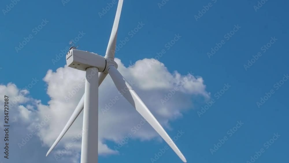 Wind turbine spins, generating power, with clouds moving in sky. Wind turbine spins, generating power, with clouds moving in sky.