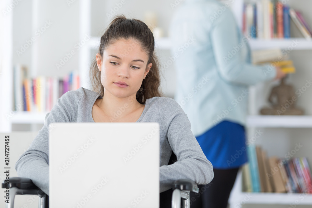 female student on the wheelchair using a laptop female student on the wheelchair using a laptop