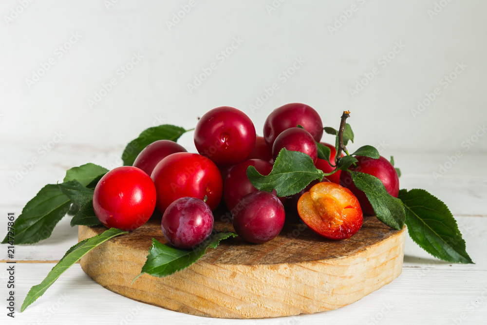 Fresh red plum with leaves on a wooden light background Fresh red plum with leaves on a wooden light background
