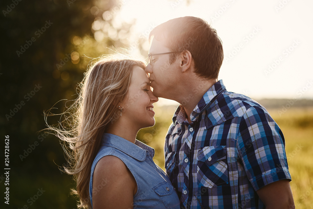 Fototapeta premium man kisses the girl on the forehead at sunset in the summer