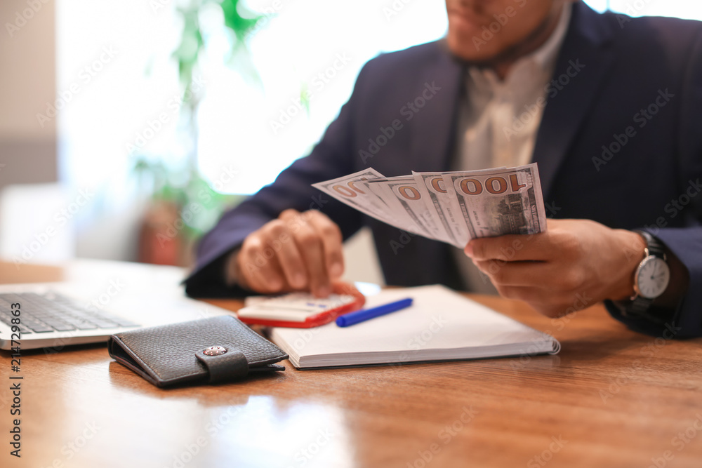 African-American businessman counting savings at table African-American businessman counting savings at table